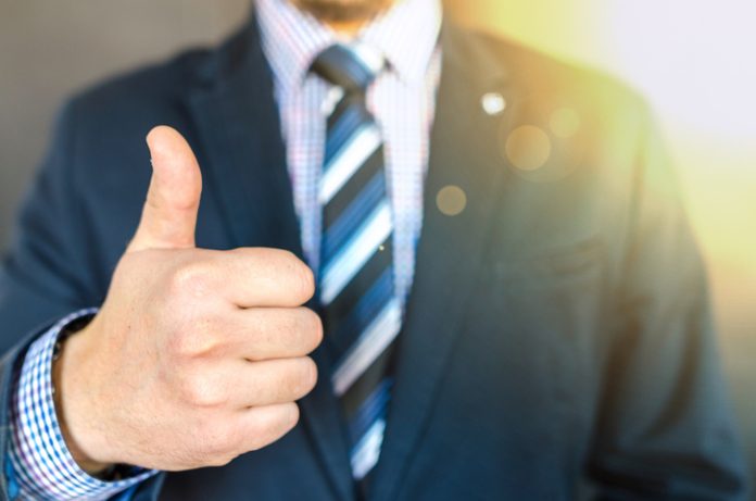 Midsection Of Businessman Gesturing Thumbs Up In Office genuine loan company