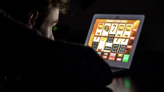 Gambling addicted man with glasses in front of online casino slot machine on laptop computer at night Ruby Fortune Casino