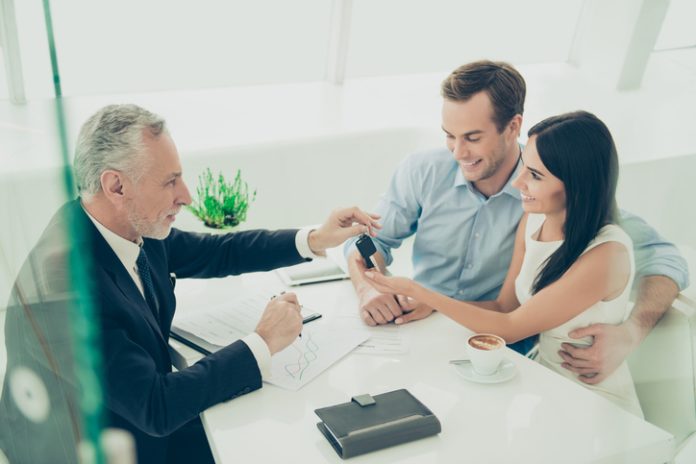 Real estate agent working with couple of customers and giving them keys Michigan real estate license
