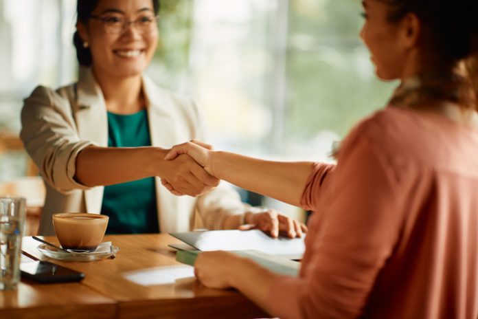 Close-up of businesswomen handshaking while greeting in a cafe. Recruitment Tips For Businesses