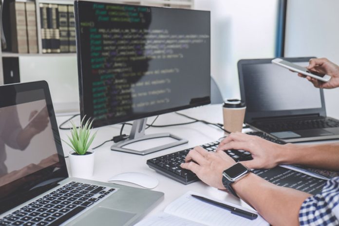 Writing codes and typing data code technology, Programmer cooperating working on web site project in a software developing on desktop computer at company