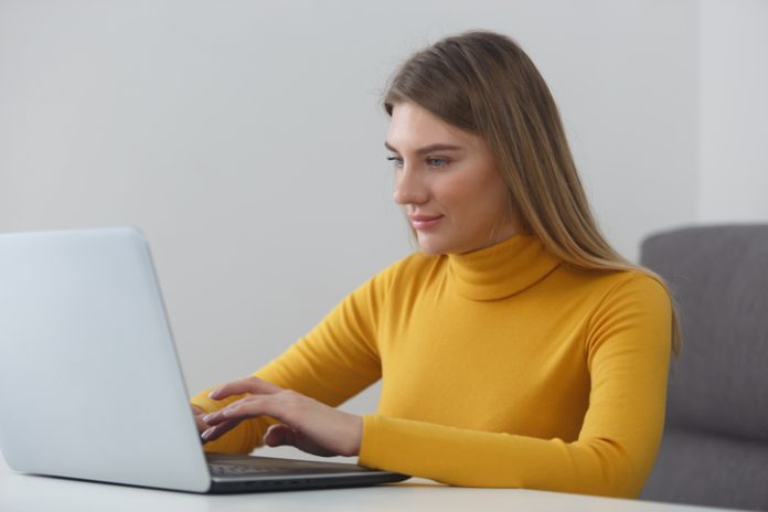 Beautiful blonde woman typing text on laptop keyboard at home. Focused white female studying online Effective Writing