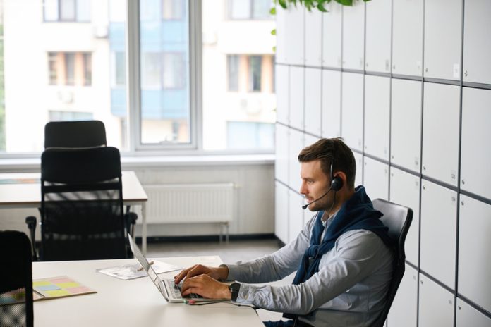 Freelancer with laptop is located in office area of coworking space transcription service provider