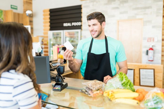 Confident Cashier With Customer In Grocery Store