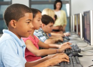 How Has Technology Affected Education and Learning? Elementary Students Working At Computers In Classroom Using Keyboard Concentrating