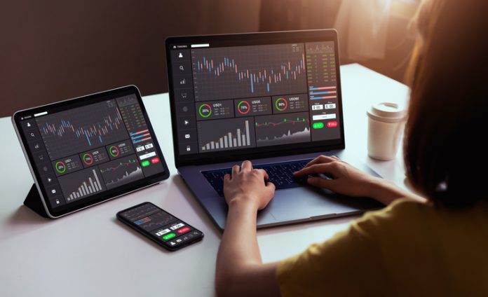 Stock exchange market concept, businesswoman trader looking on laptop and tablet, smartphone with graphs analysis candle line in office room, diagrams on screen. trading