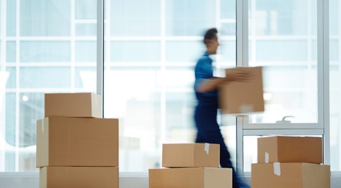 Blurred motion of contemporary worker with packed box walking to new office while delivering it to client