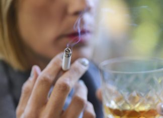 Beautiful woman drinking a glass of whiskey and smoking a cigarette