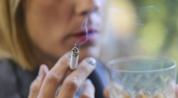 Beautiful woman drinking a glass of whiskey and smoking a cigarette