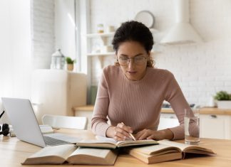 Prepare Yourself before Writing – The Most Important Tips You Should Follow Concentrated young woman in eyewear reading carefully educational handbook, improving professional knowledge or preparing for university admission exams, writing notes in copybook, learning concept.