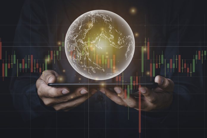 A man with tablet and a hand holding a globe graphic and stock chart Investment concepts, business concepts, technology concepts.