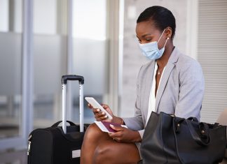 Moving to Europe for a Job During the COVID 19 Pandemic Business woman in airport with face mask checking phone