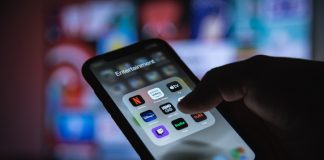 4 Best OTT Streaming Services in 2022 Apple XS Smartphone in Hand with Group of Streaming Applications