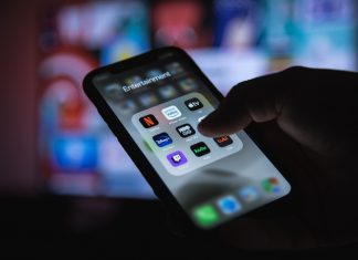 4 Best OTT Streaming Services in 2022 Apple XS Smartphone in Hand with Group of Streaming Applications