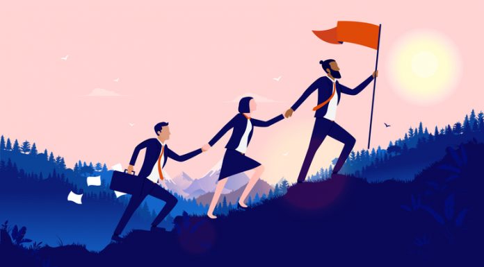 Teamwork diversity - A small group of businesspeople walking up hill to plant flag at the top