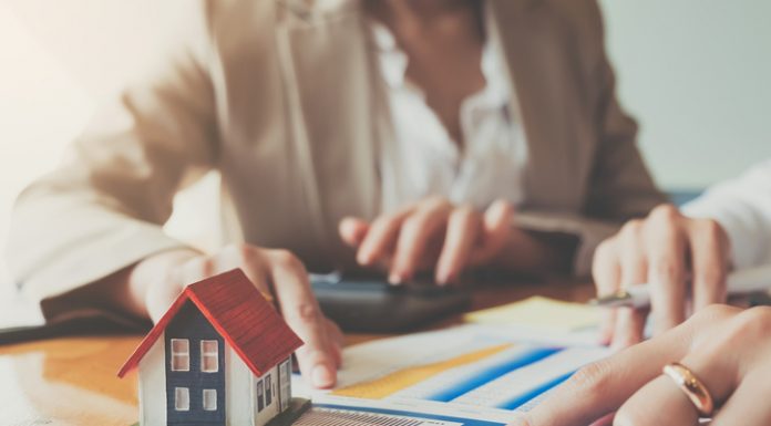 Close up hand of businesswoman signing contract Insurance protecting house.