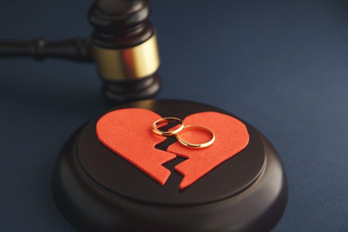 Wedding rings on the figure of a broken heart from a tree, hammer of a judge on a wooden background. Divorce divorce lawyer