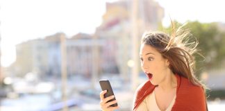 Amazed woman with smart phone content in the street