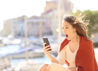 Amazed woman with smart phone content in the street