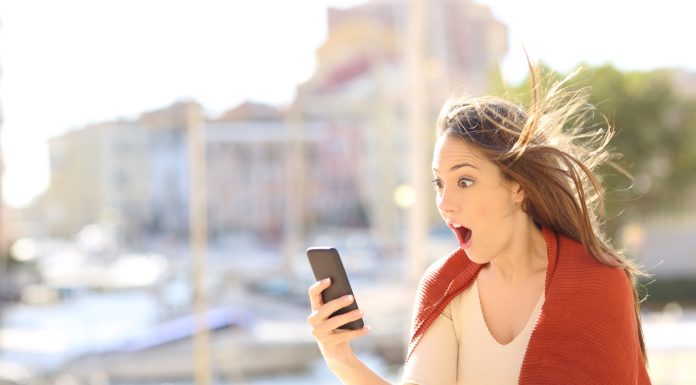 Amazed woman with smart phone content in the street