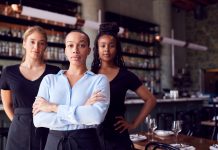 Portrait Of Female Owner Of Restaurant Bar With Team Of Waiting Staff Standing By Counter