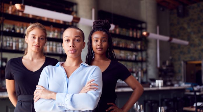 Portrait Of Female Owner Of Restaurant Bar With Team Of Waiting Staff Standing By Counter