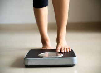 Prima Weight Loss Reviews (UK): The Hidden Truth About Prima Weight Loss Capsules In The UK? Female leg stepping on weigh scales. Healthy lifestyle, food and sport concept.