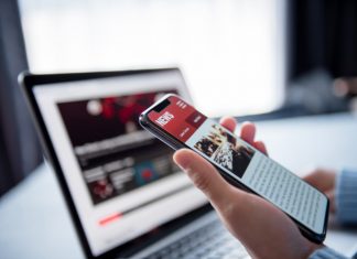 Online news on a smartphone and laptop, Woman reading news or articles in a mobile phone screen application at home. Newspaper and portal on internet.