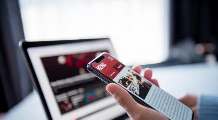 Online news on a smartphone and laptop, Woman reading news or articles in a mobile phone screen application at home. Newspaper and portal on internet.