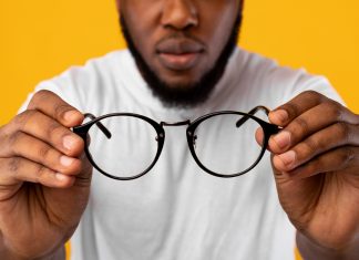 Avoid These Common Mistakes When Buying Eyeglasses African Man Holding Glasses Having Poor Eyesight, Yellow Background, Cropped
