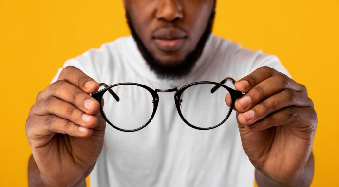 Avoid These Common Mistakes When Buying Eyeglasses African Man Holding Glasses Having Poor Eyesight, Yellow Background, Cropped