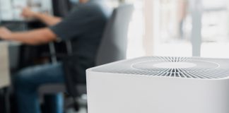 Close up Air purifier in the room is very safe and clean to breathe with filter dust PM 2.5 and a man use computer desktop working in home in clean air