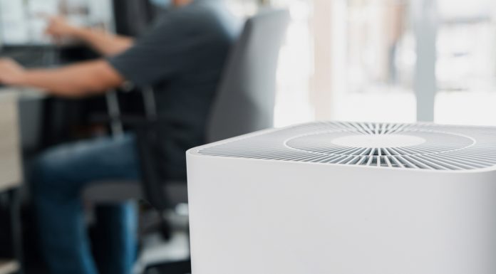 Close up Air purifier in the room is very safe and clean to breathe with filter dust PM 2.5 and a man use computer desktop working in home in clean air