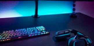 Gaming accessories on dark table. Keyboard with color backlit and stereo headphones.