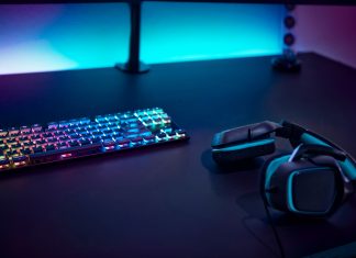 Gaming accessories on dark table. Keyboard with color backlit and stereo headphones.