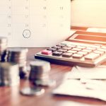 debt collection and tax season concept with deadline calendar remind note,coins,banks,calculator on table