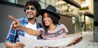 Happy black couple on vacation sightseeing city with map