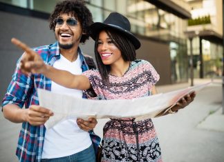 Happy black couple on vacation sightseeing city with map