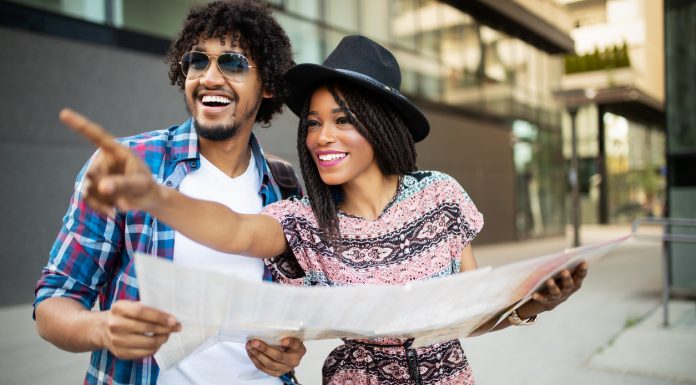Happy black couple on vacation sightseeing city with map