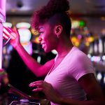 happy woman gambling at casino playing slot machine