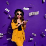 Portrait of her she nice attractive cheerful cheery positive trendy luxury wavy-haired lady throwing 100 hundred million expenses isolated over bright vivid shine violet lilac background