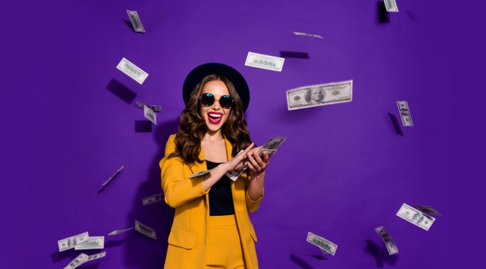Portrait of her she nice attractive cheerful cheery positive trendy luxury wavy-haired lady throwing 100 hundred million expenses isolated over bright vivid shine violet lilac background