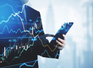 Trading and investment concept trader silhouette with digital tablet and virtual screen with financial chart graphs and candlestick.