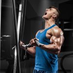 Muscular man working out in gym doing exercises at biceps, strong male