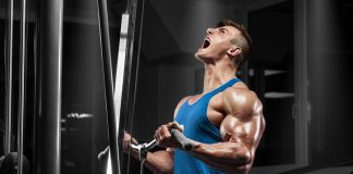 Muscular man working out in gym doing exercises at biceps, strong male