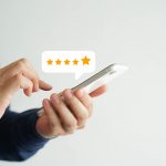 close up on customer man hand pressing on smartphone screen with five star rating feedback icon and press level good rank for giving best score point to review the service , technology business concept