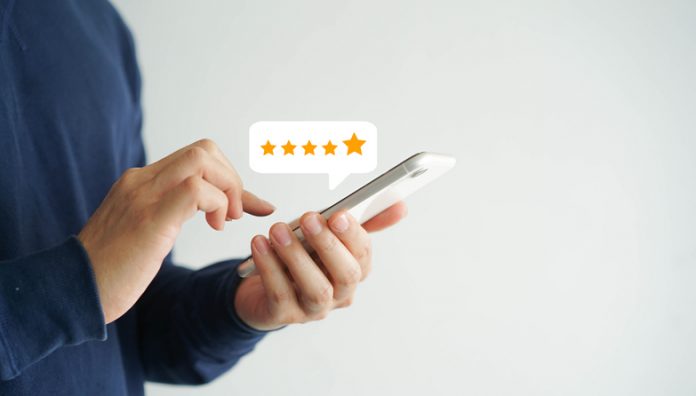 close up on customer man hand pressing on smartphone screen with five star rating feedback icon and press level good rank for giving best score point to review the service , technology business concept