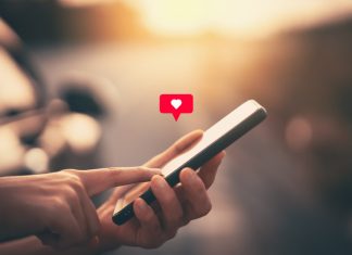 6 Ways to Never Be Lonely with Funchatt Close up woman hand hold using smart phone with heart icon at outdoor park street background. Copy space of technology business and travel holiday concept.