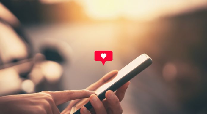 6 Ways to Never Be Lonely with Funchatt Close up woman hand hold using smart phone with heart icon at outdoor park street background. Copy space of technology business and travel holiday concept.