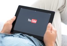 man holding iPad with app YouTube on the screen